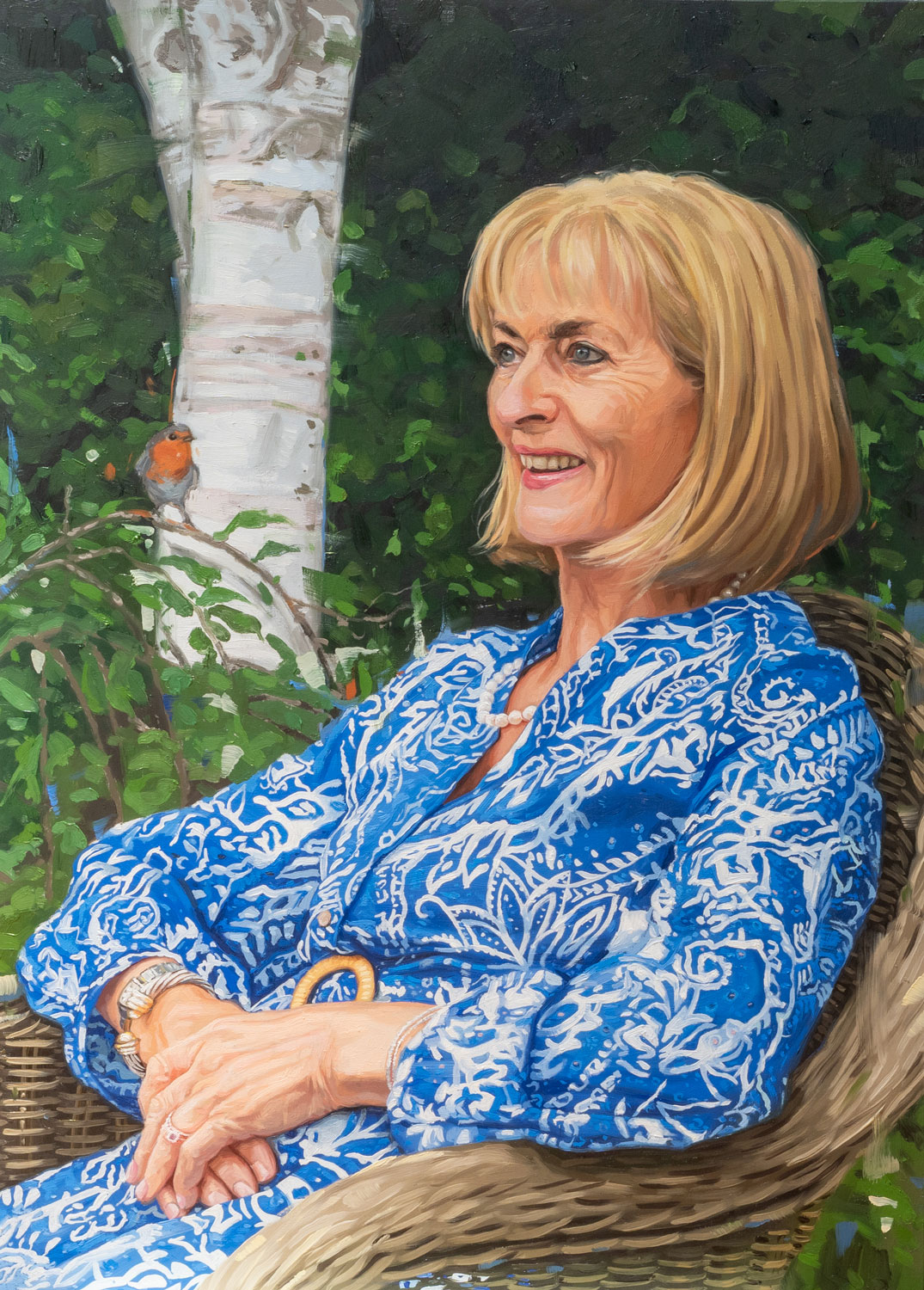 Carole Portrait oil painting of a lady in her garden with a robin and silver birch in the background.